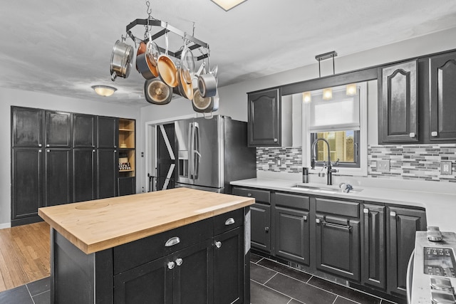 kitchen featuring backsplash, sink, hanging light fixtures, dark hardwood / wood-style floors, and stainless steel fridge with ice dispenser