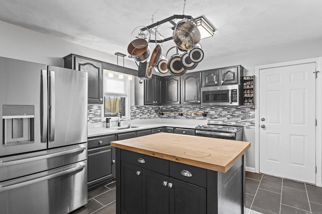 kitchen with sink, stainless steel appliances, backsplash, a kitchen island, and dark tile patterned flooring