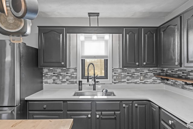 kitchen with tasteful backsplash, stainless steel refrigerator, and sink