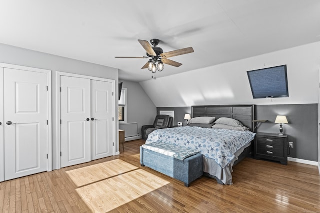 bedroom with ceiling fan, hardwood / wood-style floors, a baseboard radiator, and vaulted ceiling