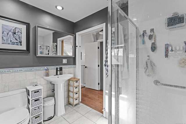 bathroom with toilet, tile patterned flooring, tile walls, and walk in shower