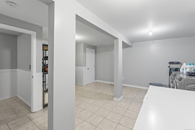 basement featuring washing machine and dryer and light tile patterned floors