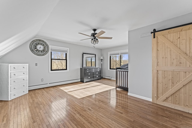 bonus room with a baseboard heating unit, vaulted ceiling, hardwood / wood-style flooring, ceiling fan, and a barn door