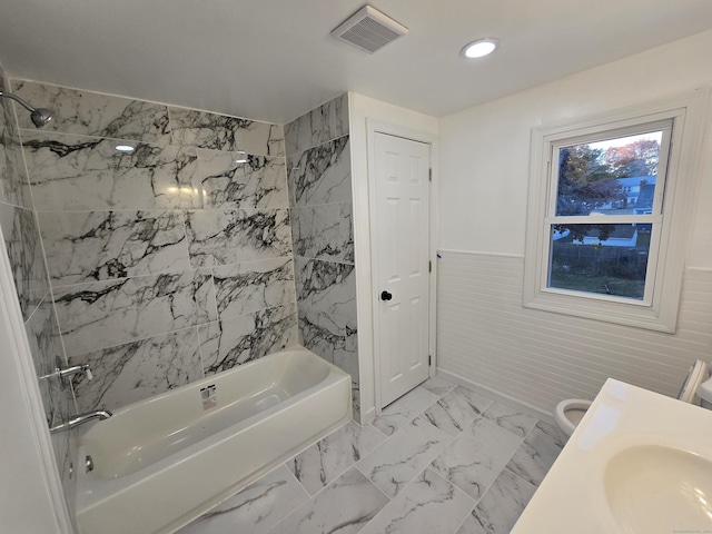 bathroom with marble finish floor, a wainscoted wall, visible vents, a sink, and  shower combination