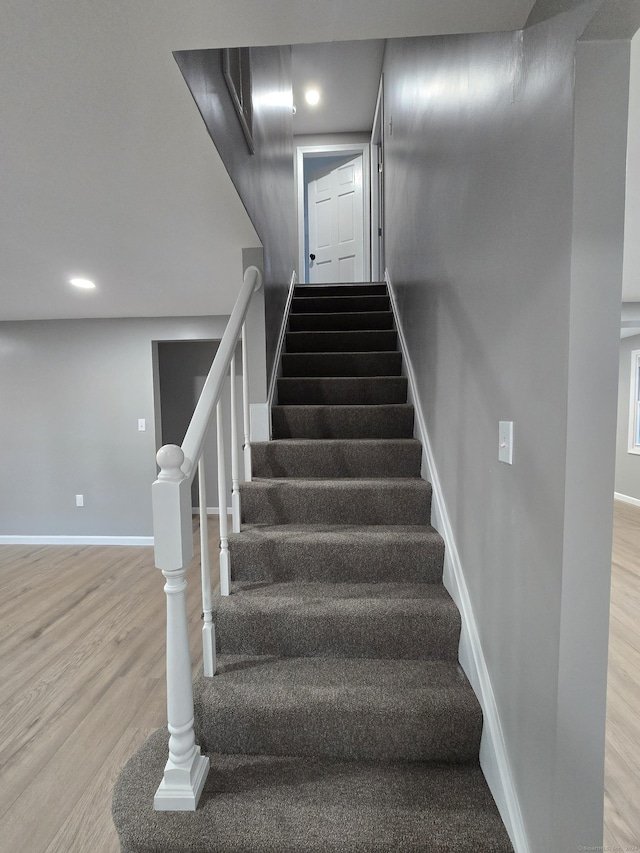 stairs featuring baseboards, wood finished floors, and recessed lighting