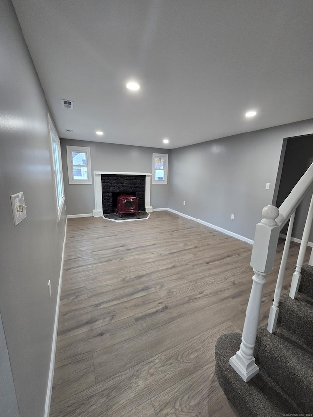 living room featuring wood finished floors, visible vents, baseboards, and stairs