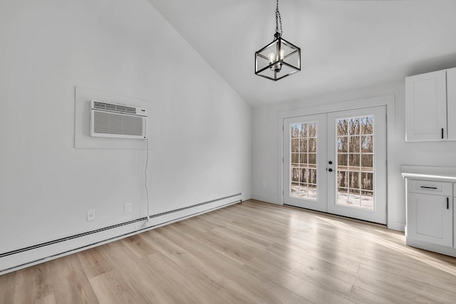 unfurnished dining area featuring french doors, baseboard heating, an AC wall unit, a chandelier, and light wood-type flooring