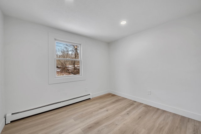 unfurnished room with light wood-type flooring and a baseboard radiator