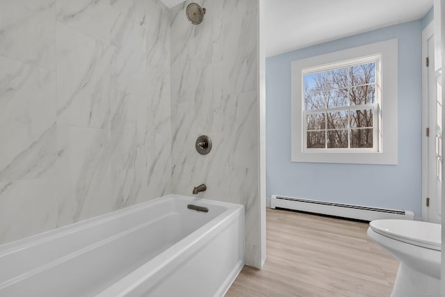 bathroom with hardwood / wood-style floors, toilet, tiled shower / bath, and a baseboard radiator