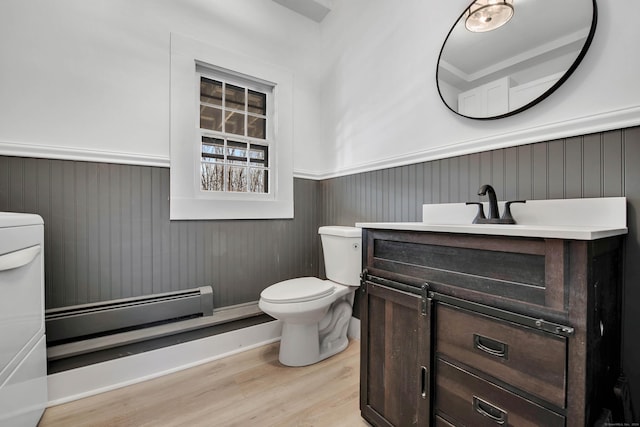 bathroom with a baseboard radiator, washer / clothes dryer, toilet, vanity, and hardwood / wood-style flooring