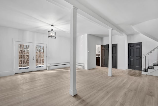 unfurnished living room featuring a notable chandelier, french doors, a baseboard radiator, and light hardwood / wood-style flooring