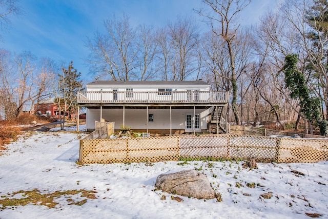 snow covered back of property with french doors and a wooden deck