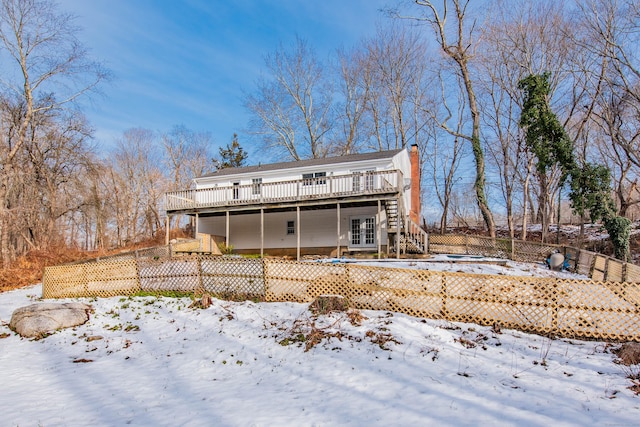 snow covered house with french doors and a deck