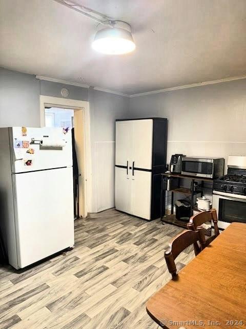 kitchen with light hardwood / wood-style flooring, white appliances, and ornamental molding