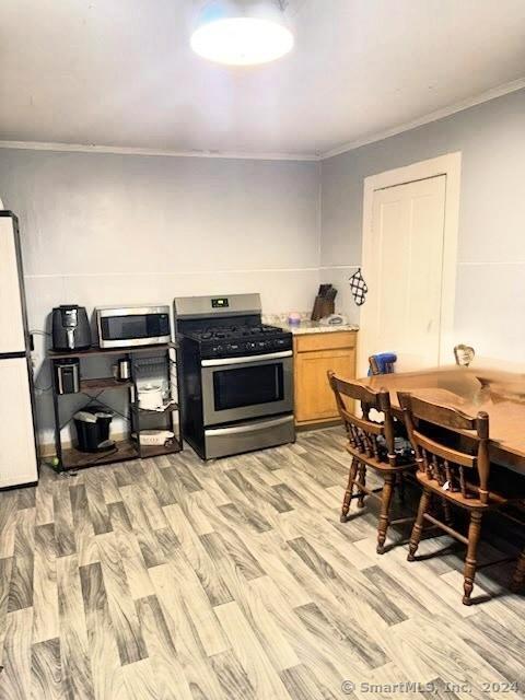 kitchen with crown molding, stainless steel appliances, and light hardwood / wood-style floors