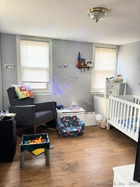 bedroom with hardwood / wood-style floors and a nursery area