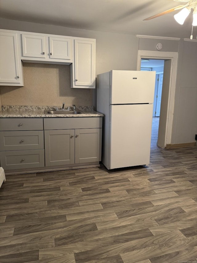 kitchen with dark wood-style flooring, gray cabinets, freestanding refrigerator, white cabinetry, and a sink