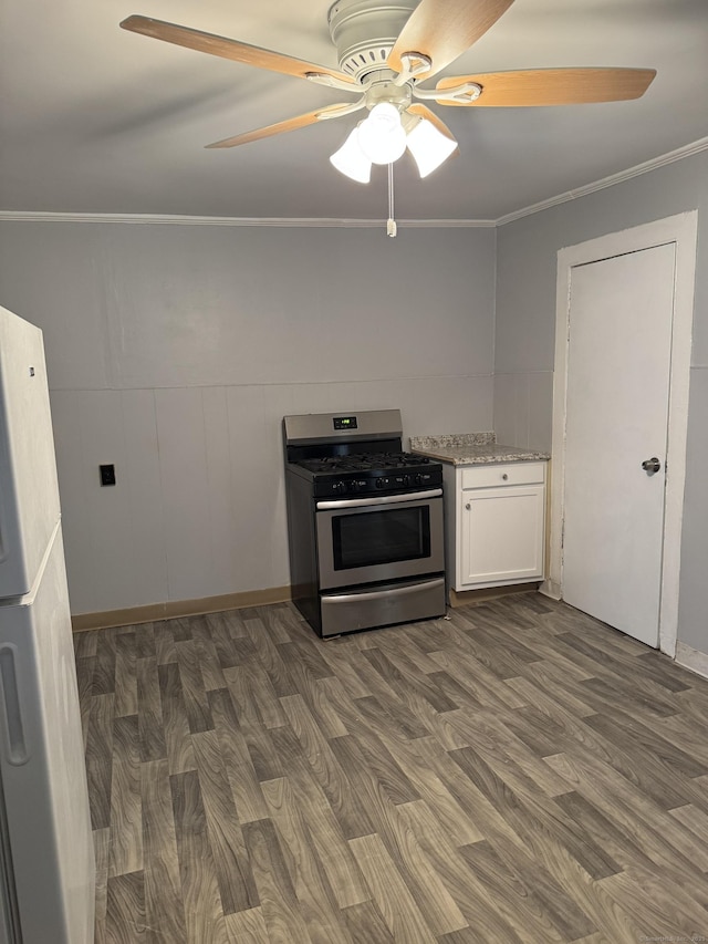 kitchen featuring dark wood-type flooring, white cabinetry, stainless steel range with gas stovetop, and crown molding