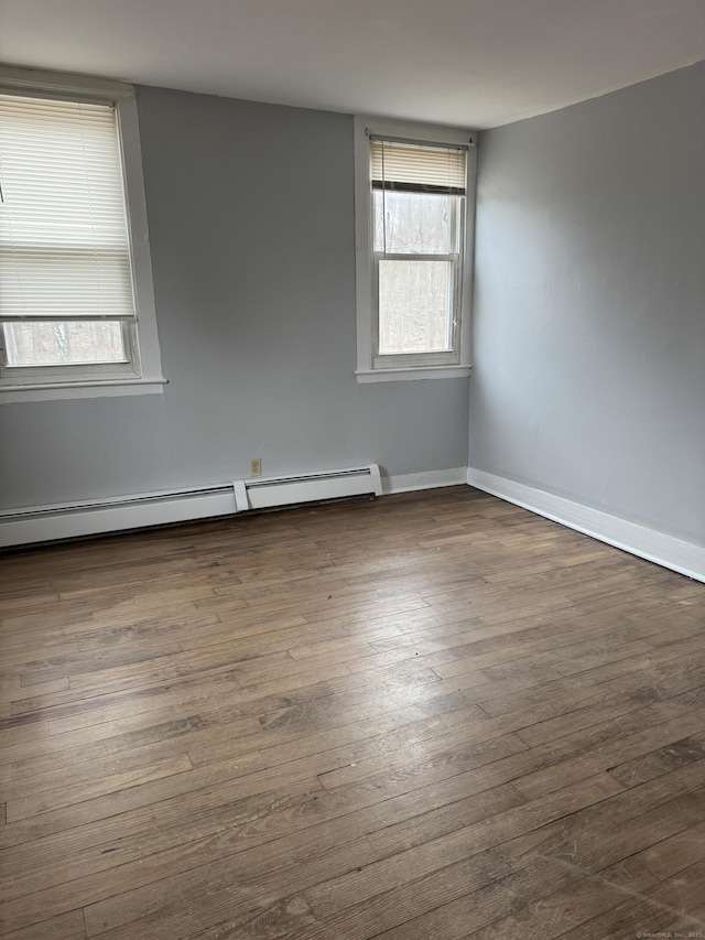 unfurnished room with a baseboard radiator, a healthy amount of sunlight, dark wood finished floors, and baseboards