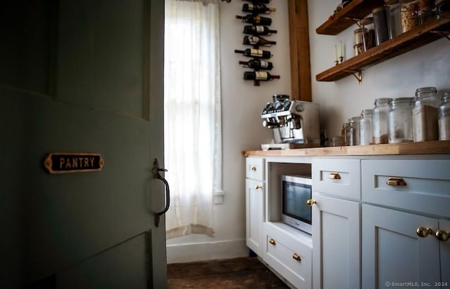 bar featuring white cabinets and a healthy amount of sunlight