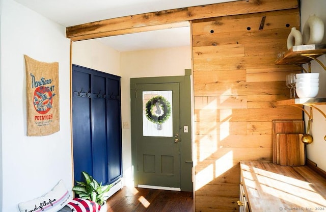 foyer entrance with wood walls, dark hardwood / wood-style floors, and beam ceiling