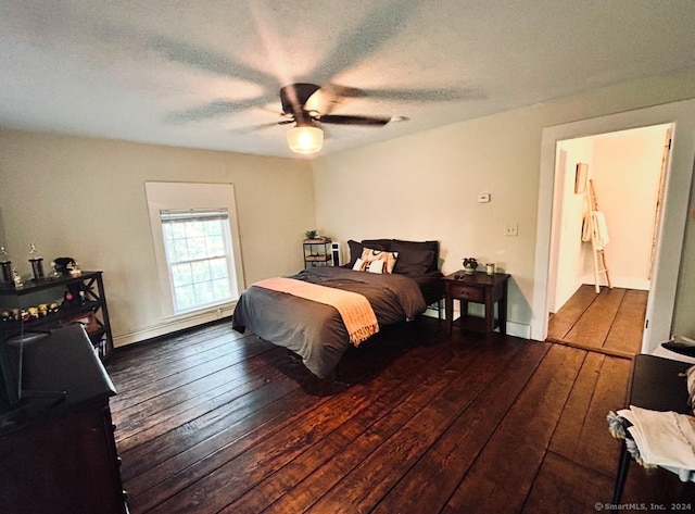 bedroom with a textured ceiling, ceiling fan, and dark hardwood / wood-style floors