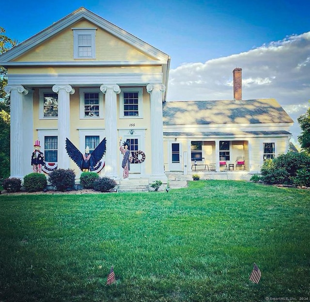 neoclassical home featuring a front yard and covered porch