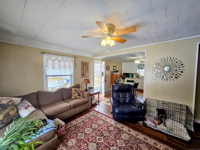 living area with ceiling fan, wood finished floors, and crown molding