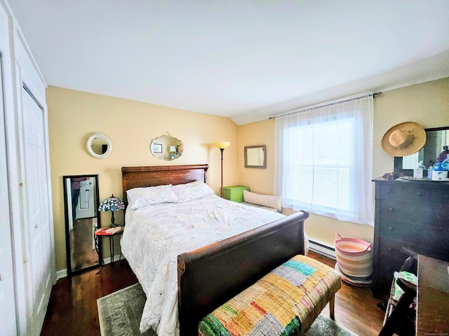 bedroom featuring dark wood-style floors, a baseboard heating unit, and baseboards