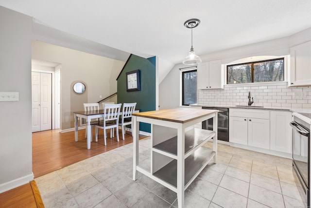 kitchen with sink, black appliances, light hardwood / wood-style floors, white cabinetry, and hanging light fixtures