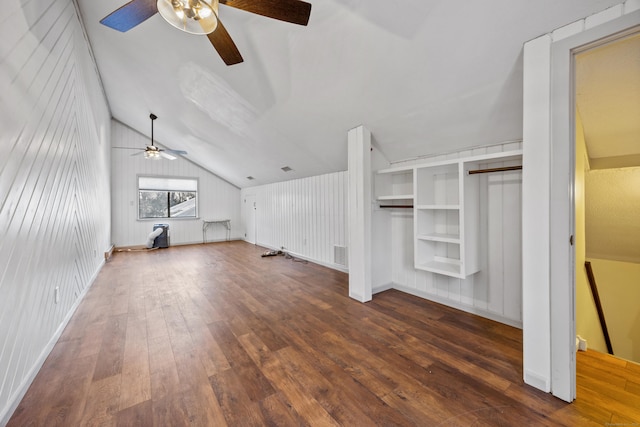 additional living space featuring wooden walls, vaulted ceiling, dark hardwood / wood-style floors, ceiling fan, and built in features