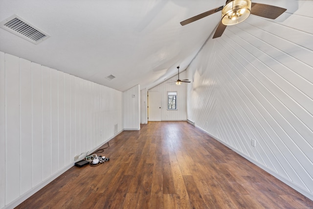 unfurnished living room featuring dark hardwood / wood-style floors, vaulted ceiling, and wood walls