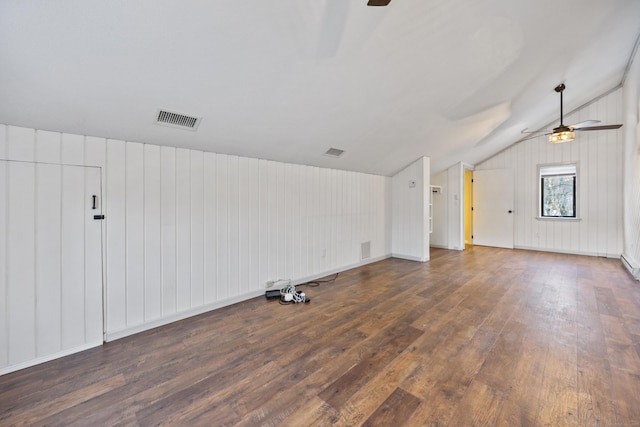 empty room featuring dark hardwood / wood-style floors, ceiling fan, lofted ceiling, and wood walls