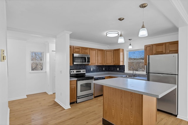 kitchen featuring appliances with stainless steel finishes, sink, a center island, light hardwood / wood-style floors, and hanging light fixtures