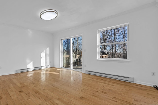 spare room with a healthy amount of sunlight, light hardwood / wood-style flooring, and a baseboard heating unit