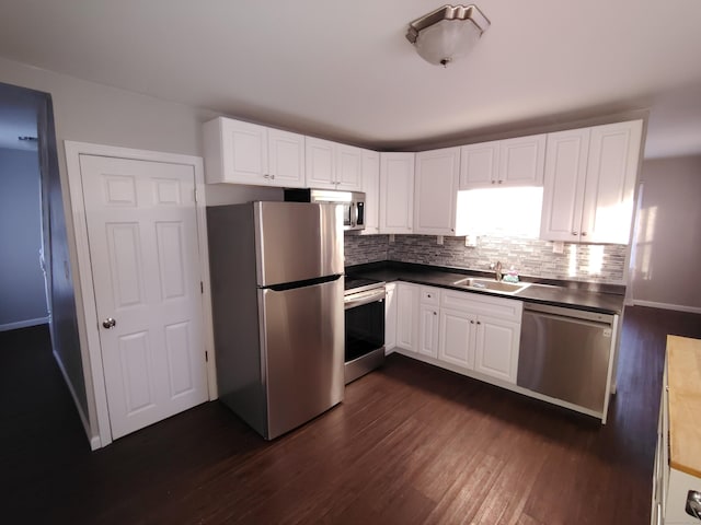 kitchen featuring appliances with stainless steel finishes, backsplash, dark wood-type flooring, sink, and white cabinets