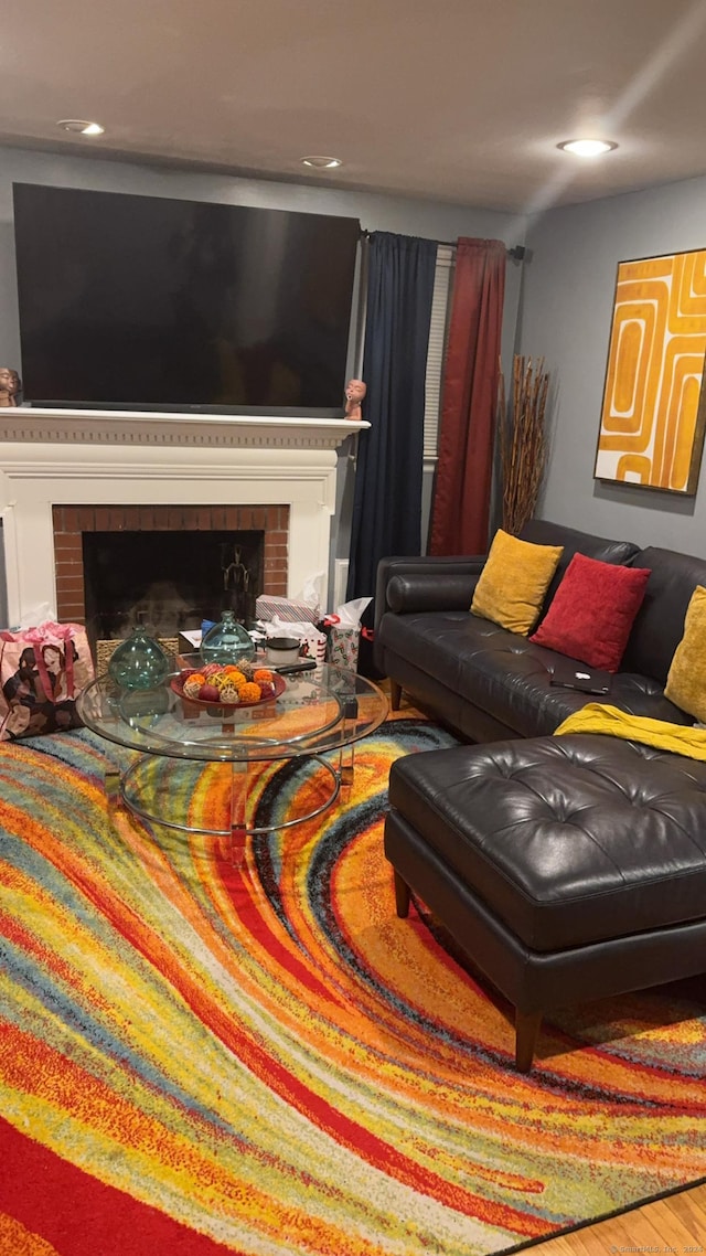 living room with hardwood / wood-style flooring and a brick fireplace