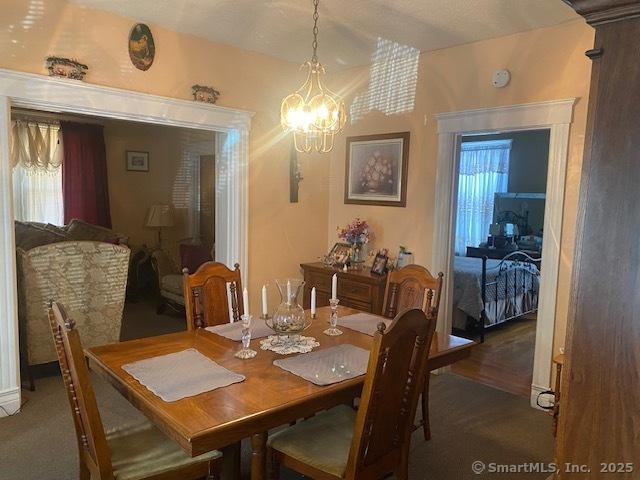 carpeted dining space featuring an inviting chandelier