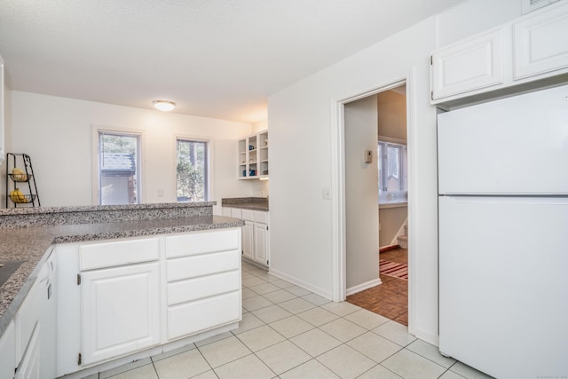 kitchen with white cabinetry, white fridge, and light tile patterned floors