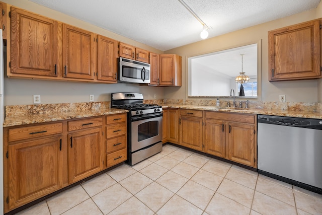 kitchen with sink, stainless steel appliances, an inviting chandelier, a textured ceiling, and light tile patterned flooring