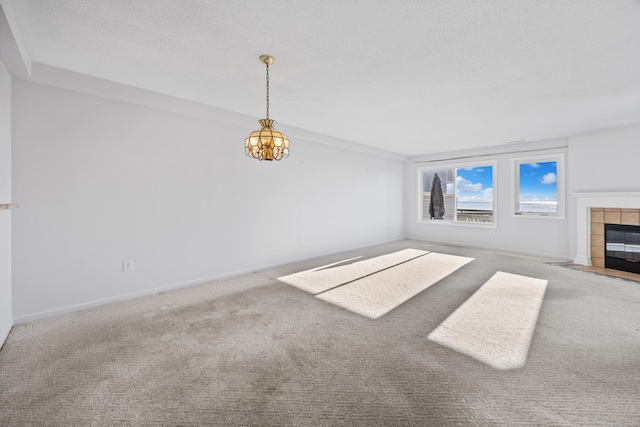 unfurnished living room with carpet flooring, a fireplace, and a chandelier