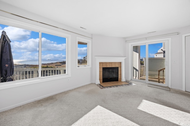 unfurnished living room featuring carpet floors and a tiled fireplace