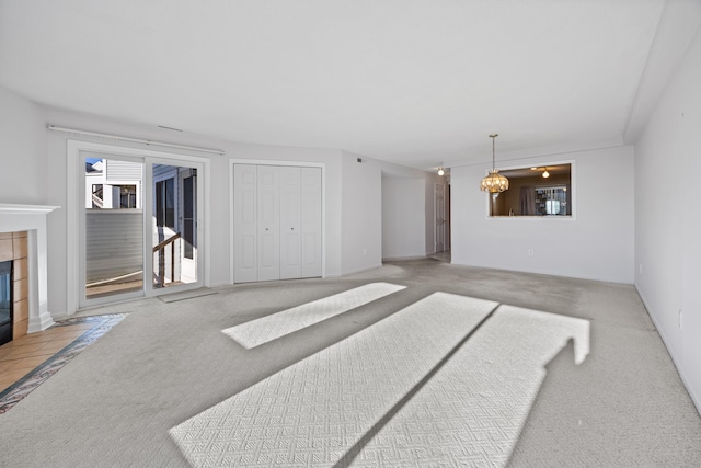 living room featuring a tile fireplace, light carpet, and a chandelier