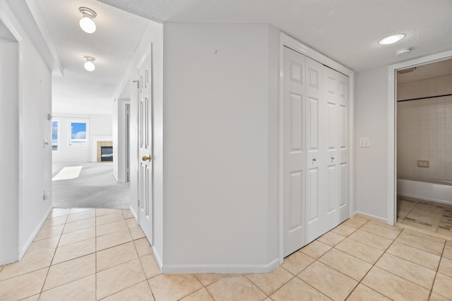 hallway featuring light tile patterned floors and a textured ceiling