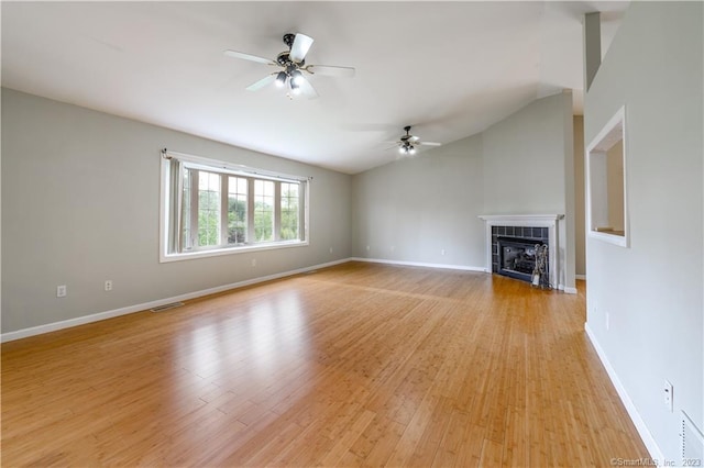 unfurnished living room featuring ceiling fan, a fireplace, vaulted ceiling, and light wood-type flooring