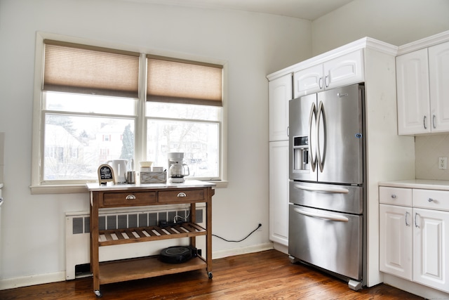 kitchen with radiator, white cabinetry, decorative backsplash, hardwood / wood-style flooring, and stainless steel fridge with ice dispenser