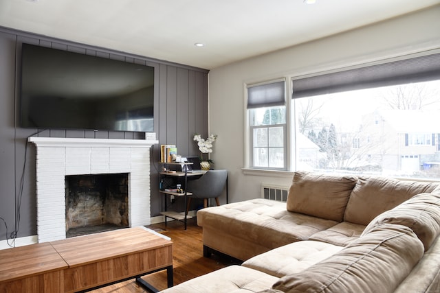 living room featuring a brick fireplace and hardwood / wood-style flooring