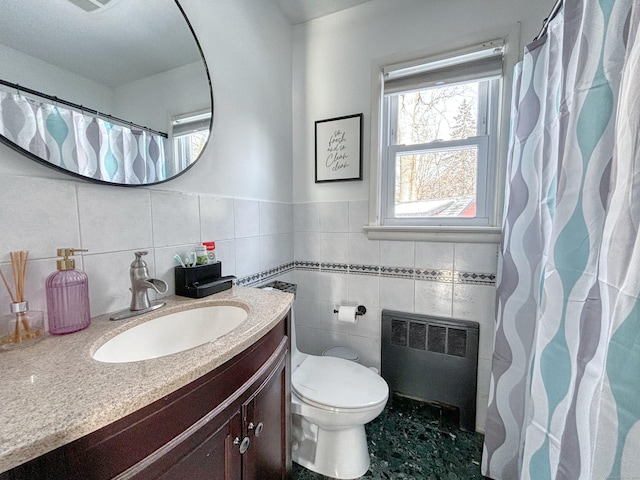 bathroom with vanity, toilet, radiator, and tile walls