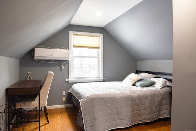 bedroom featuring hardwood / wood-style flooring, lofted ceiling, and an AC wall unit