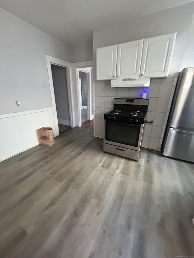 kitchen with appliances with stainless steel finishes, light hardwood / wood-style floors, white cabinetry, and tile walls